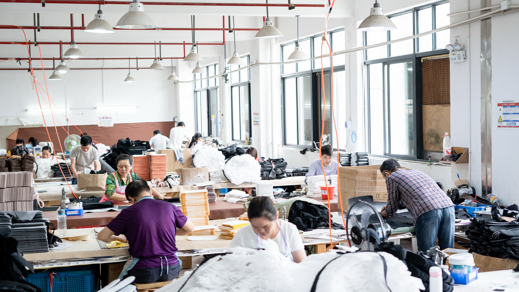 Workers preparing bag materials at factory tables