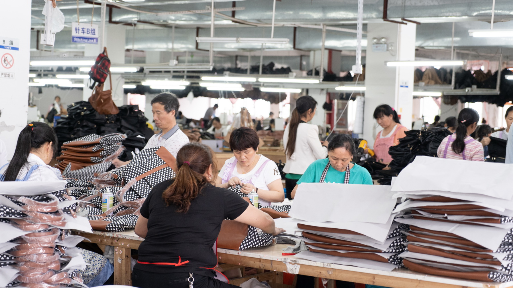 Workers assembling bags at a production table