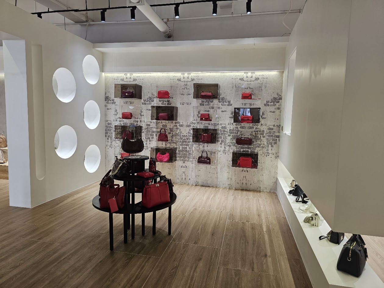 Showroom with handbags displayed on wall shelves and a central table